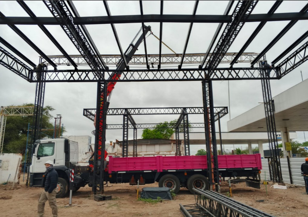 Hidrogrúa GeoLift Palfinger montando estructura metálica, carrocería rosada